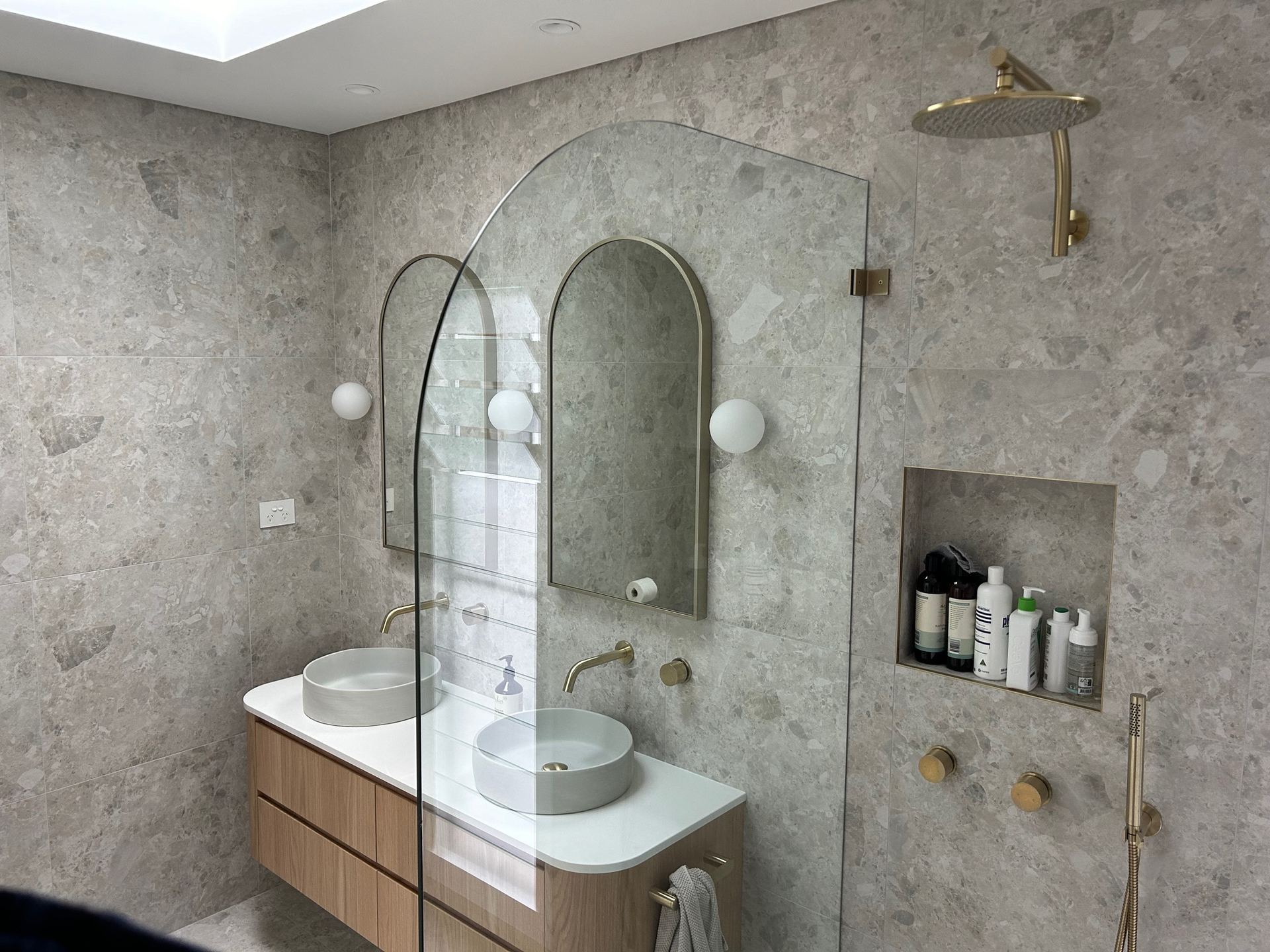 Finished ensuite with arched mirrors and stone-look tiling