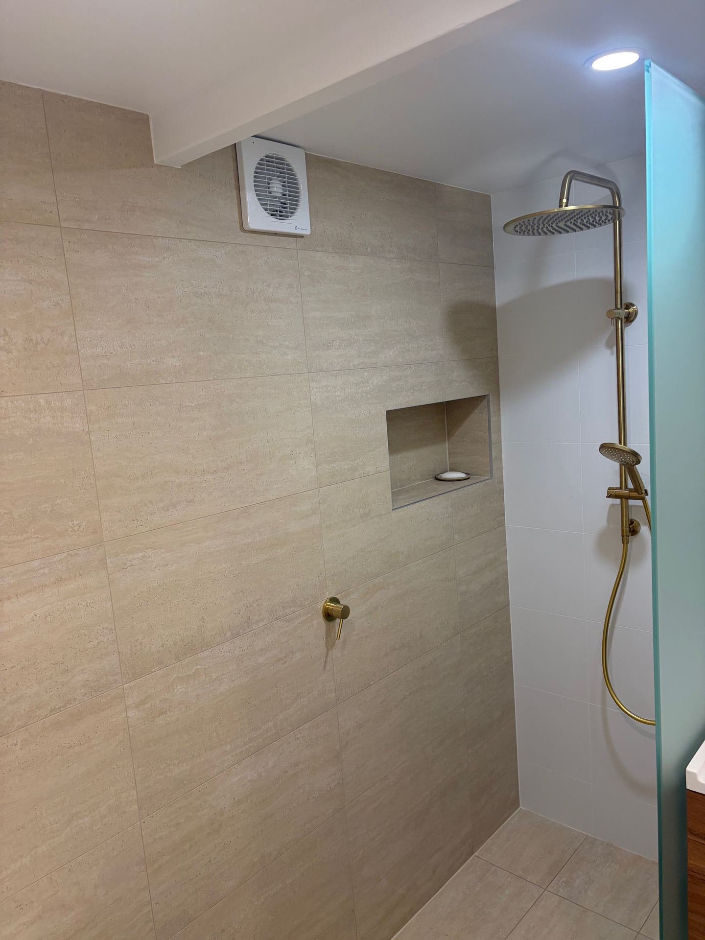 Modern walk-in shower with brass shower head and niche