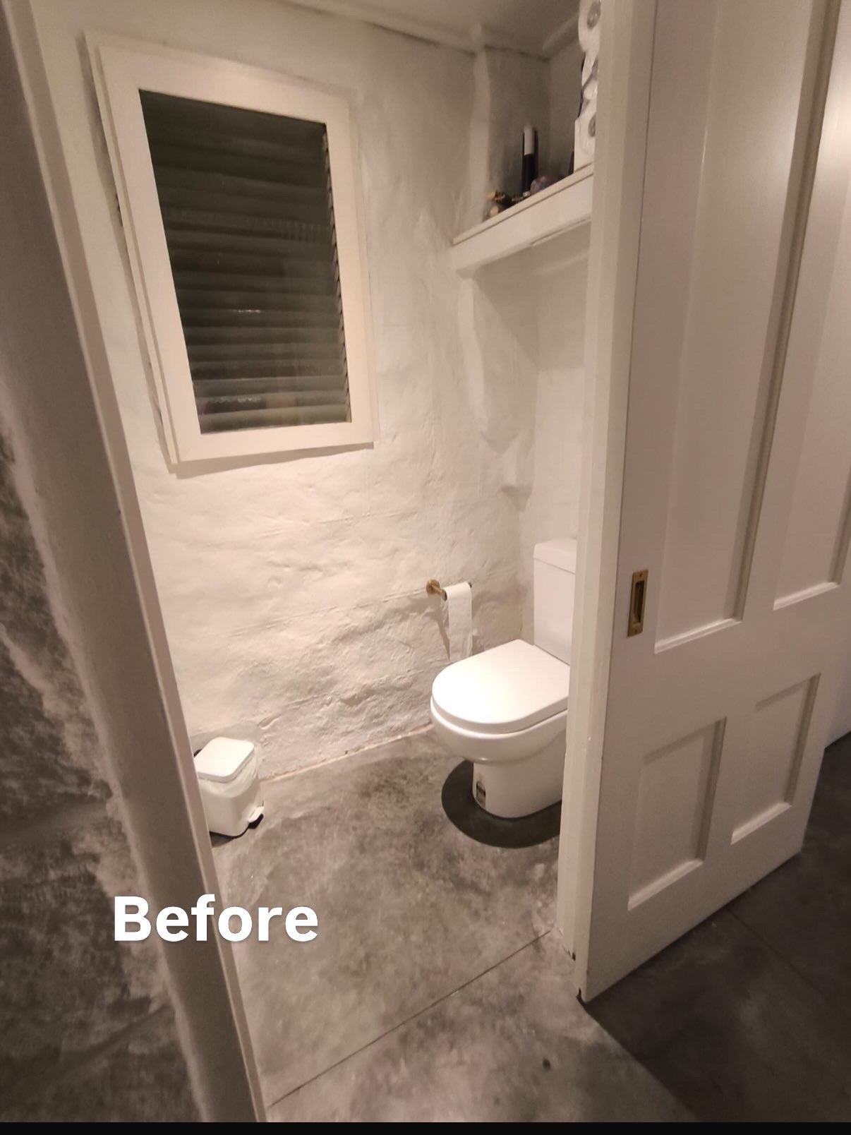 Bathroom before renovation showing old toilet and worn walls