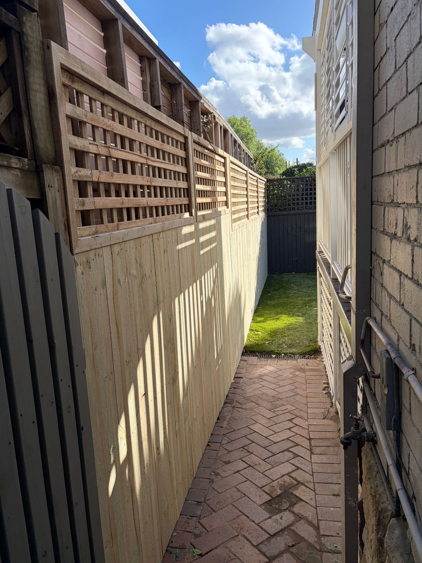 Timber deck framing under construction against a herringbone brick wall